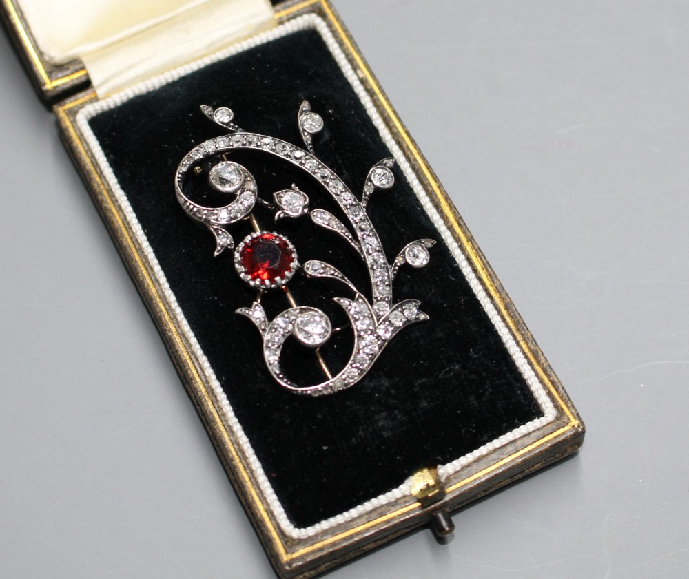 An early 20th century yellow and white metal, red spinel and diamond set foliate scroll brooch,